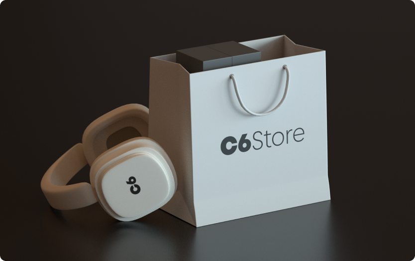Sacola C6 Store com caixas e fone branco com logo “C6” sobre fundo escuro. Cena sugere produtos tecnológicos.