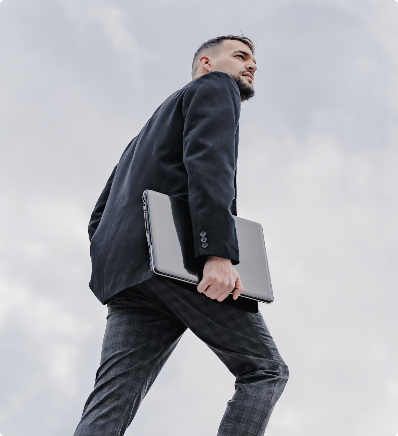 Foto de homem de terno segurando um notebook em seu braço direito