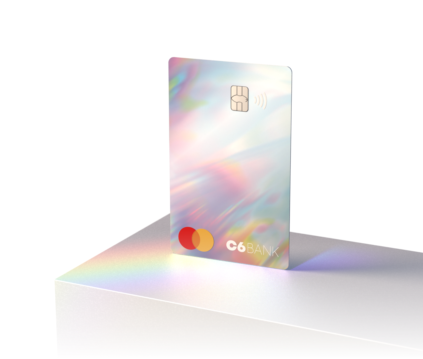 Cartão C6 Rainbow com visual holográfico em pé sobre superfície clara.